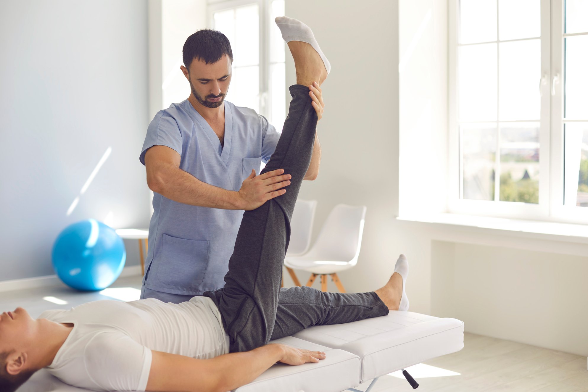 Young Doctor Examining Young Man's Leg to Assign the Right Therapy after Sports Injury